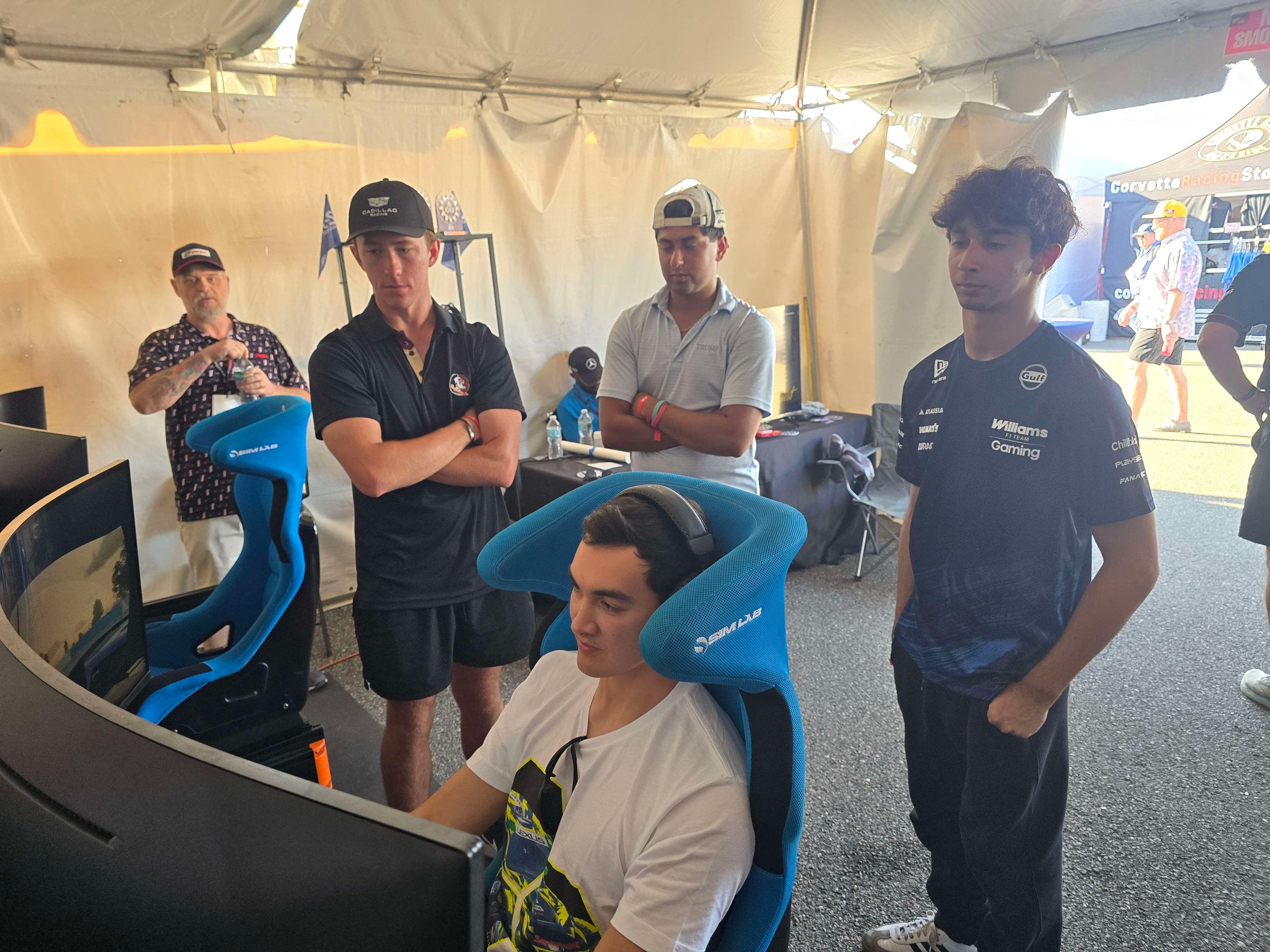 Professional racing drivers watching fans compete on the simulators